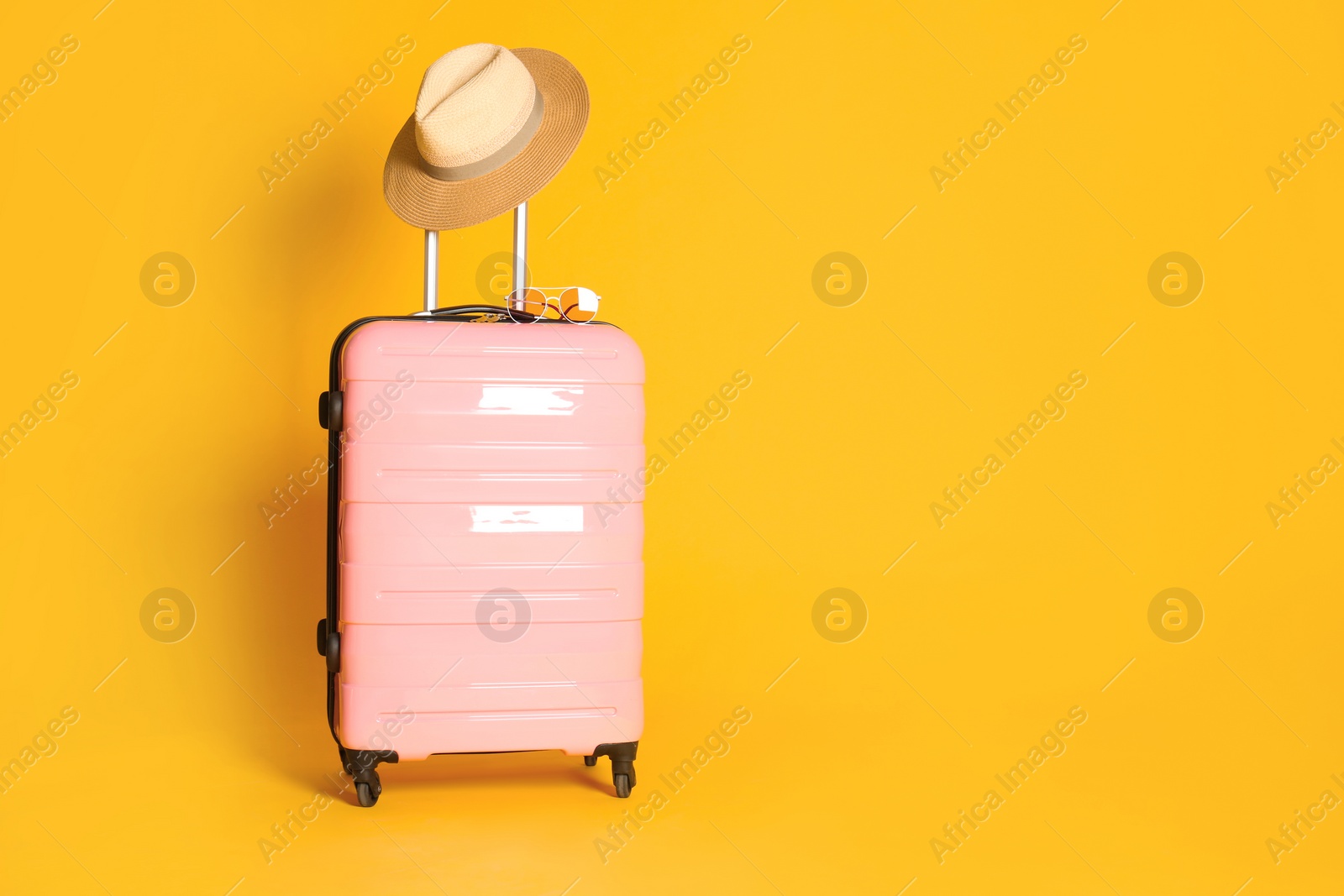 Photo of Travel suitcase with hat and sunglasses on yellow background, space for text. Summer vacation