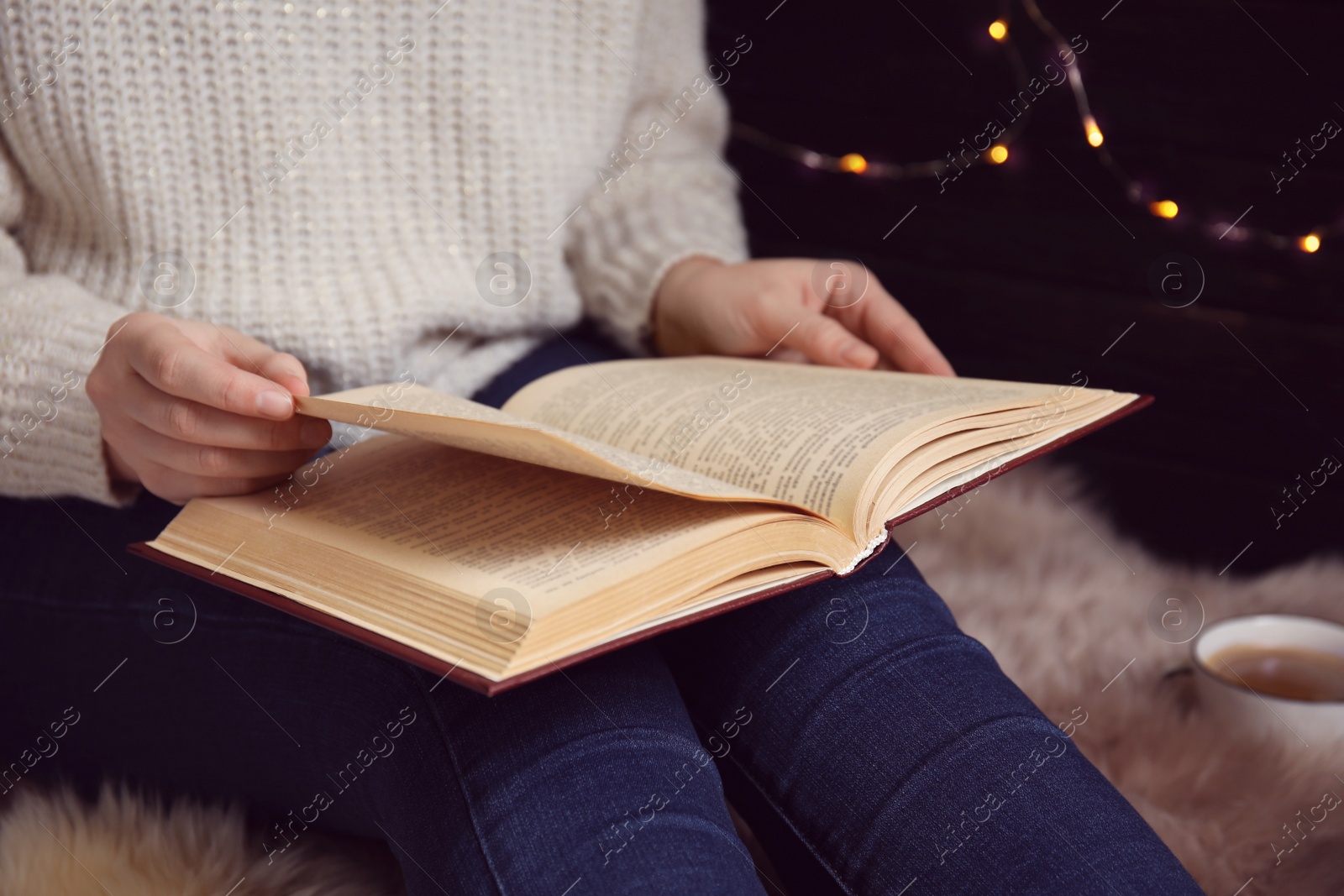 Photo of Young woman reading book at home, closeup