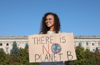 Photo of African American young woman with poster protesting against climate change outdoors