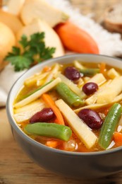 Photo of Bowl of delicious turnip soup on wooden table, closeup