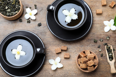 Flat lay composition with tea and fresh jasmine flowers on wooden table