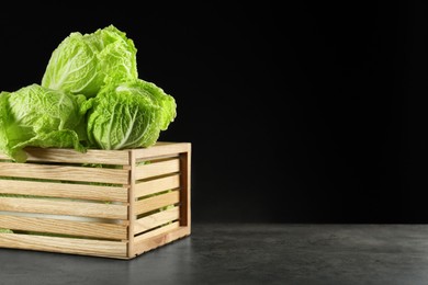 Photo of Fresh ripe Chinese cabbages in wooden crate on grey table, space for text