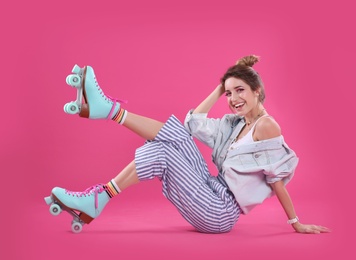 Young woman with retro roller skates on color background