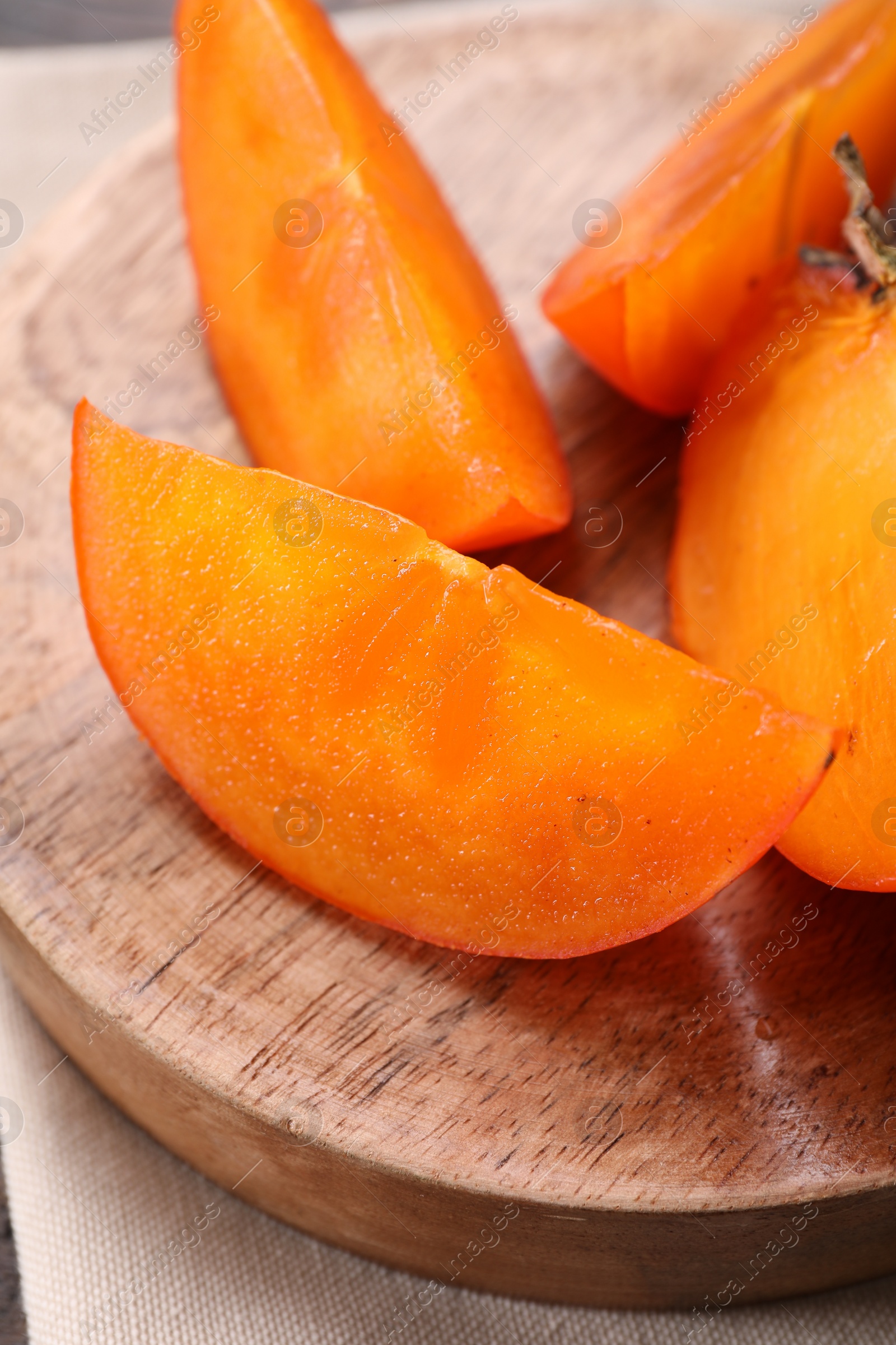 Photo of Pieces of delicious persimmons on wooden board, closeup