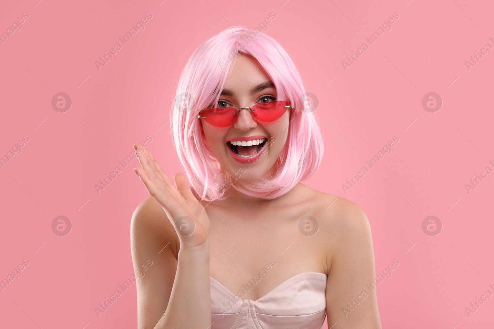 Photo of Pink look. Beautiful girl in wig and bright sunglasses on color background