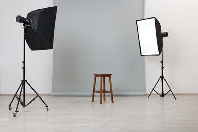 Photo of Empty stool surrounded by professional lighting equipment in photo studio