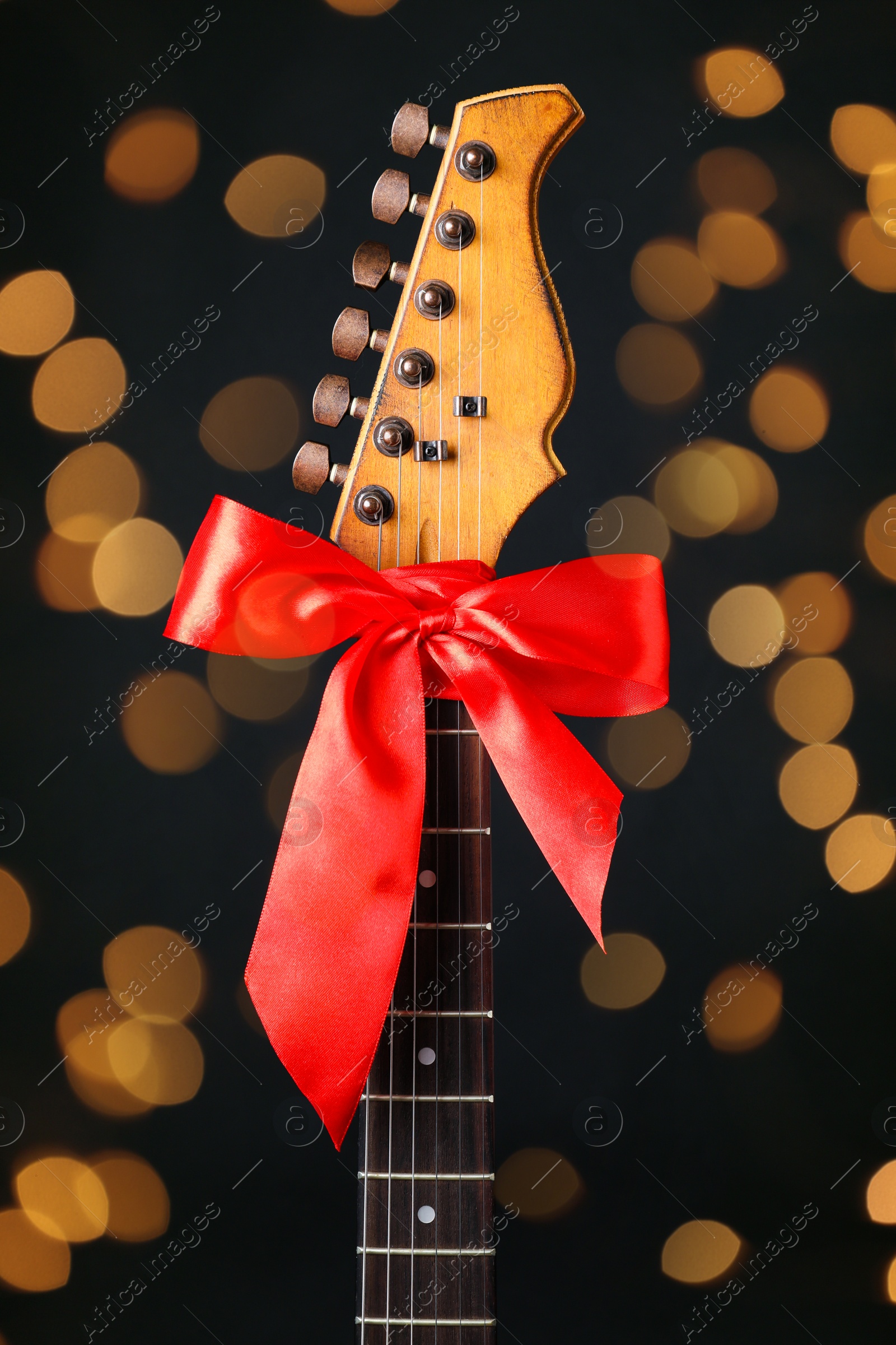 Photo of Guitar with red bow on black background. Christmas music