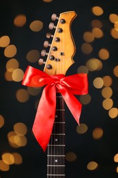 Photo of Guitar with red bow on black background. Christmas music