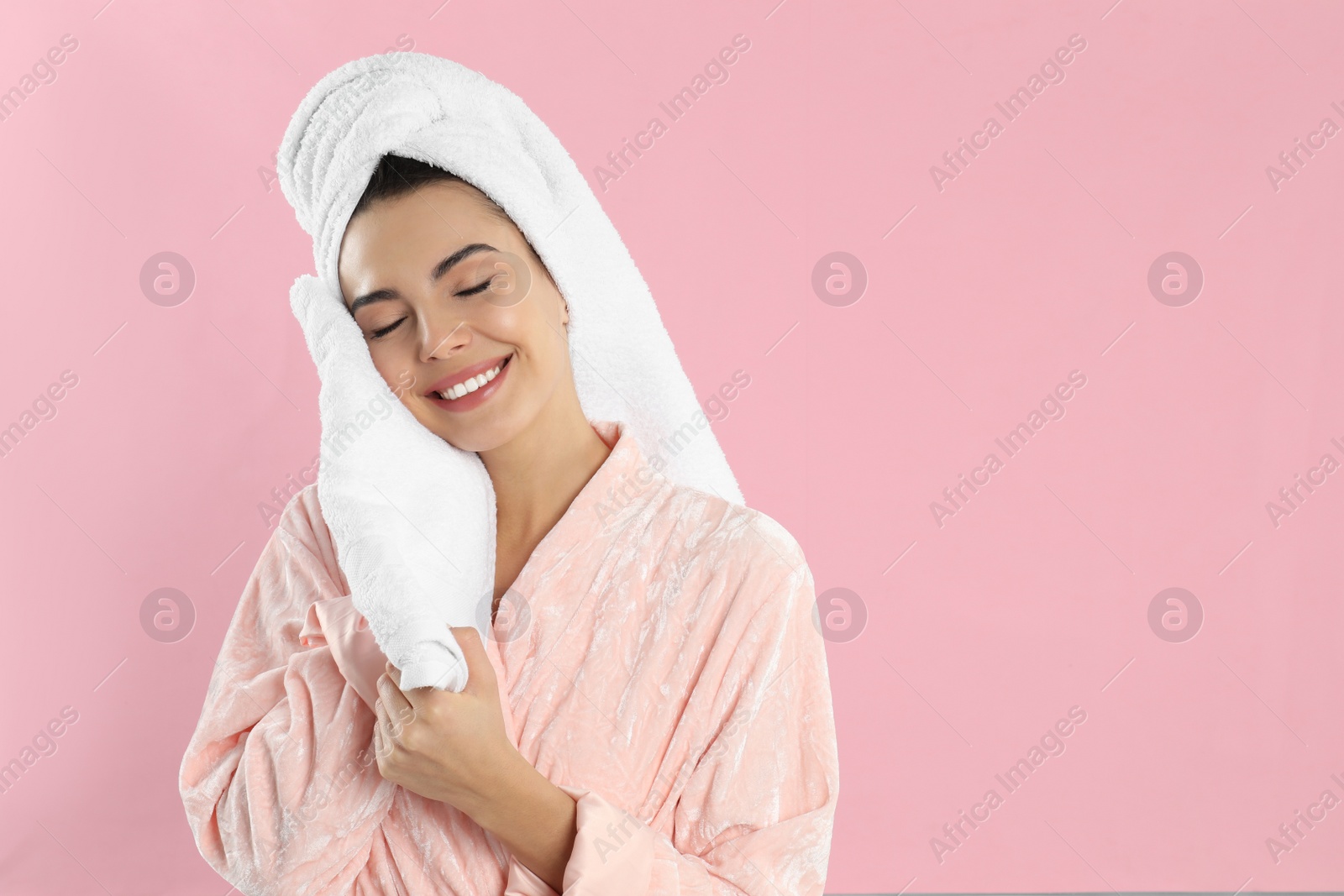 Photo of Young woman wiping face with towel on pink background. Space for text