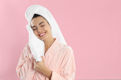 Photo of Young woman wiping face with towel on pink background. Space for text