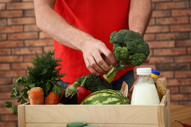 Photo of Man with fresh products at table indoors, closeup. Food delivery service