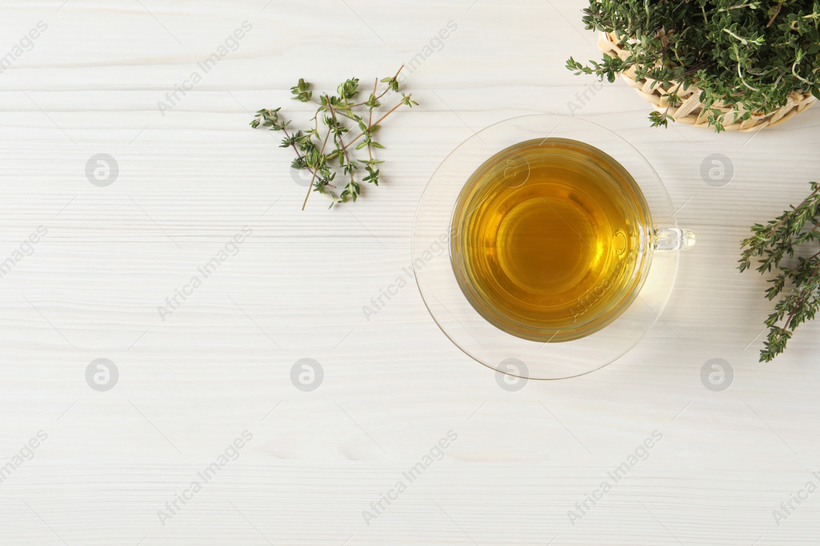 Photo of Aromatic herbal tea with thyme on white wooden table, flat lay. Space for text