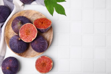 Photo of Fresh ripe purple figs on white tiled table, flat lay. Space for text