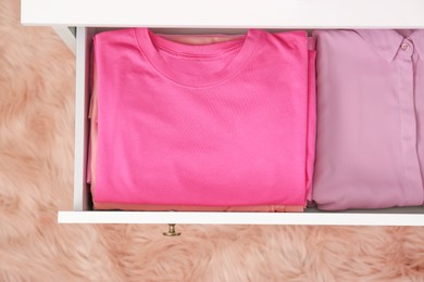 Photo of Folded pink clothes in white chest of drawers indoors, top view
