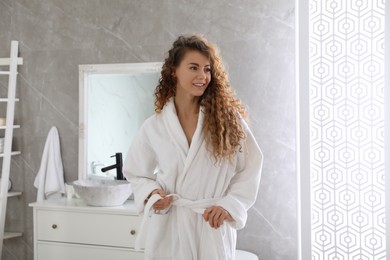 Photo of Beautiful woman wearing soft white robe in bathroom