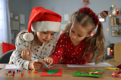 Cute little children making beautiful Christmas greeting cards at home