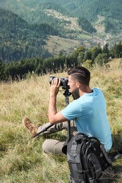 Photo of Professional photographer taking picture with modern camera in mountains