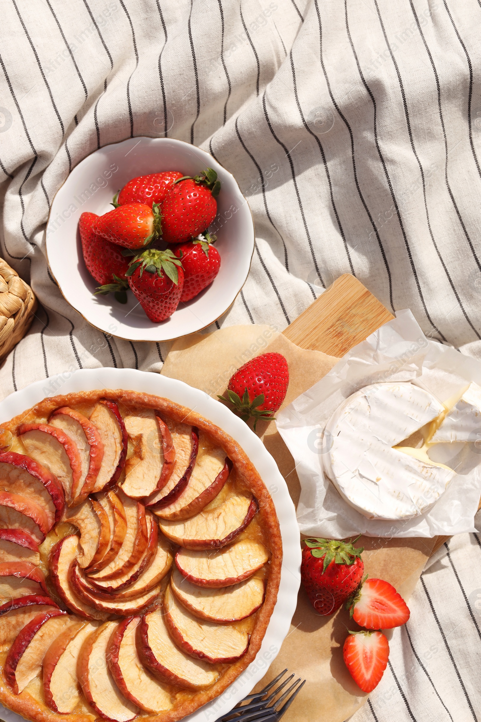 Photo of Strawberries, brie cheese and apple pie on blanket, flat lay. Summer picnic