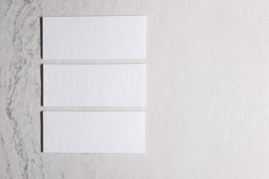 Blank business cards on beige textured background, top view. Mockup for design