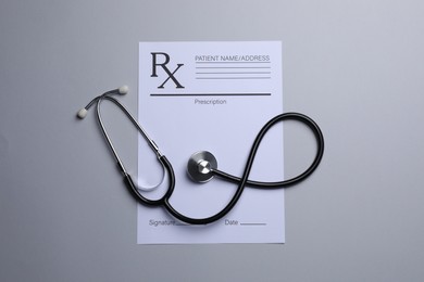 Medical prescription form and stethoscope on light grey background, flat lay