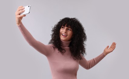 Photo of Beautiful young woman taking selfie on light grey background