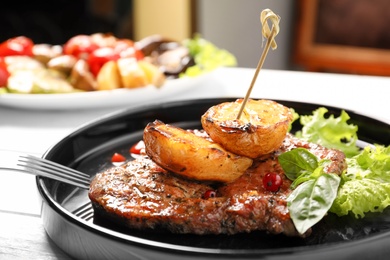 Photo of Plate with tasty grilled meat and potatoes on table, closeup