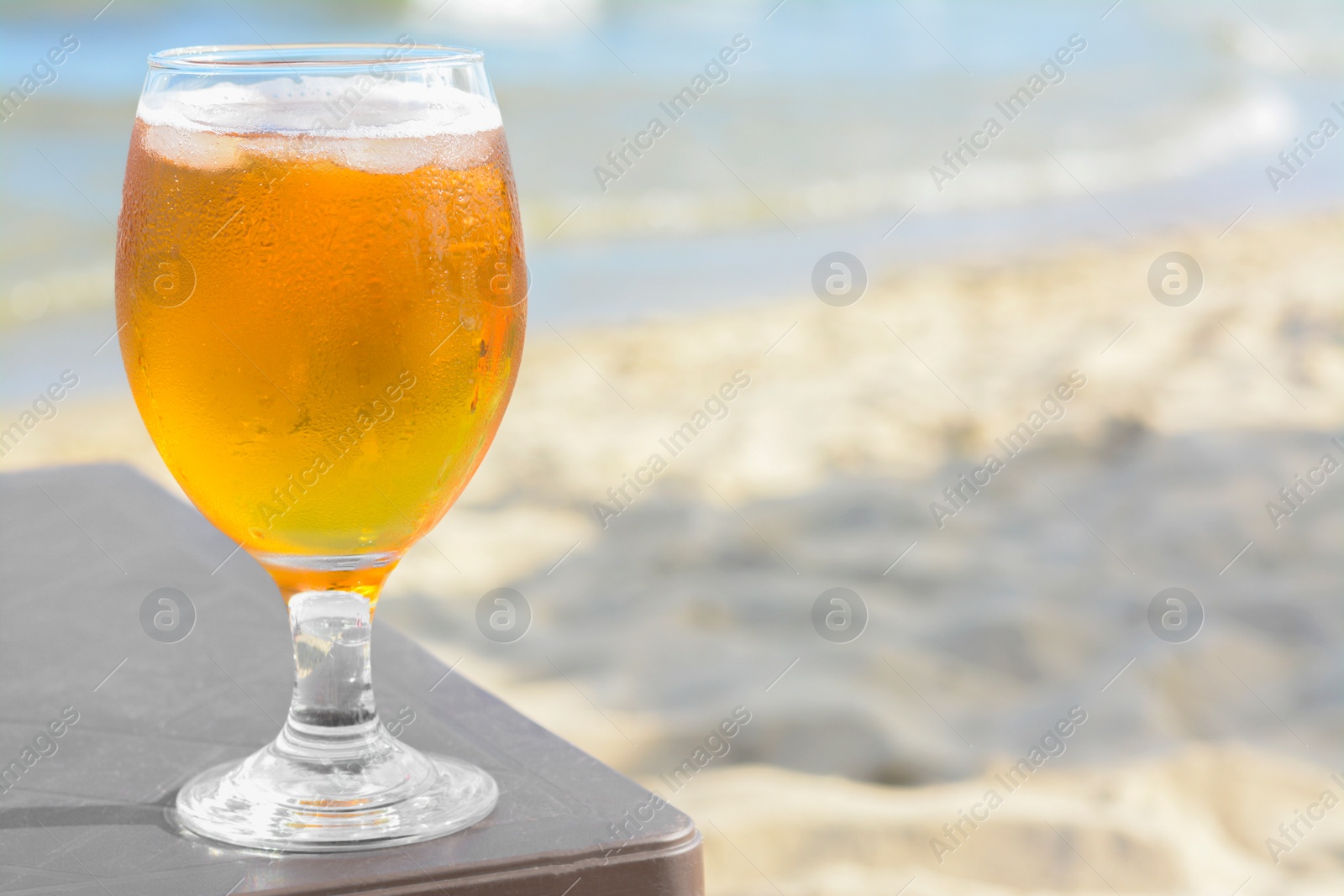 Photo of Cold beer in glass on beach. Space for text