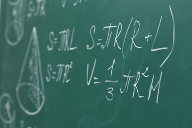 Different math formulas written with chalk on green board