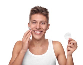 Photo of Handsome man cleaning face with cotton pad on white background