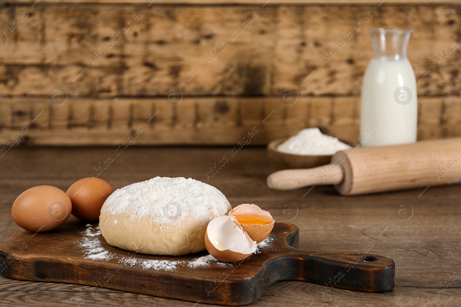 Photo of Raw eggs and dough on wooden table. Baking pie