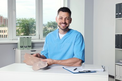 Photo of Handsome male orthopedist showing insoles in hospital