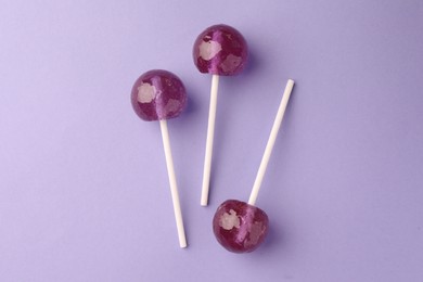 Tasty lollipops on violet background, flat lay