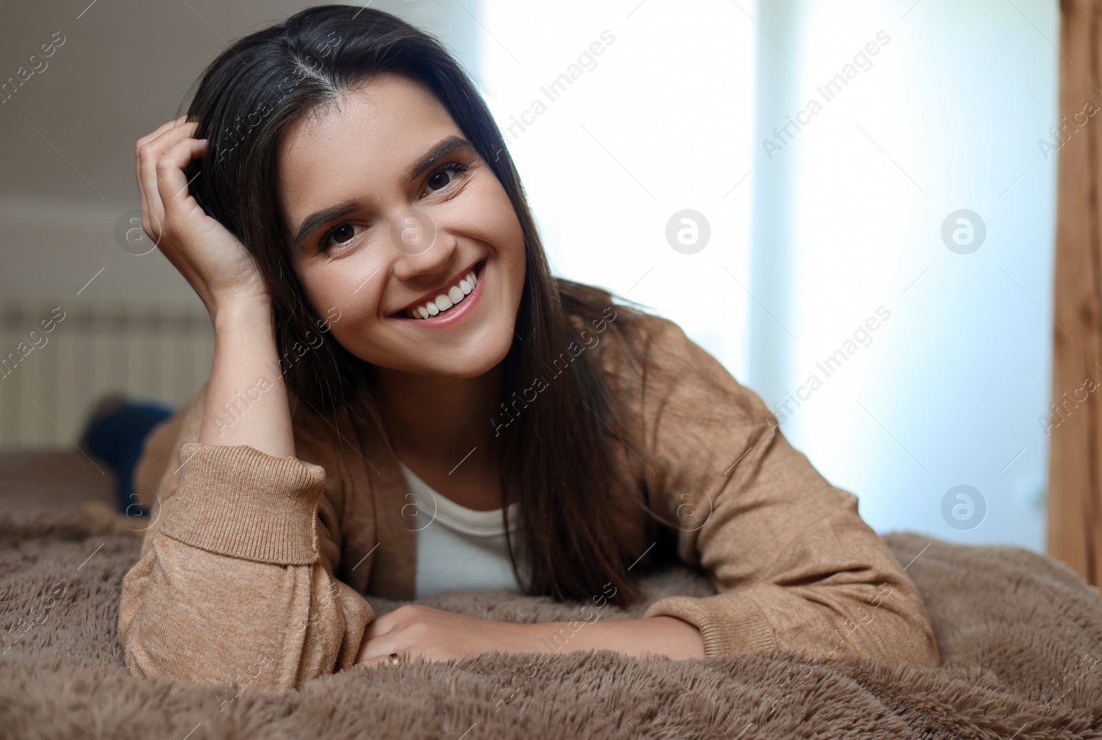 Photo of Portrait of beautiful young woman lying on bed at home