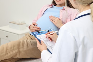 Photo of Doctor with results of laboratory test consulting pregnant patient in clinic, closeup