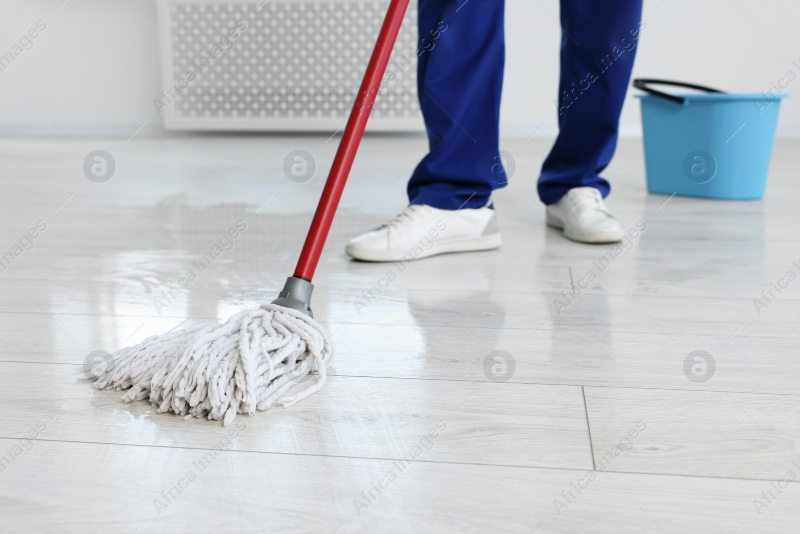 Photo of Man cleaning floor with mop indoors, closeup