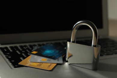 Credit cards, lock and laptop on table, closeup. Cyber crime