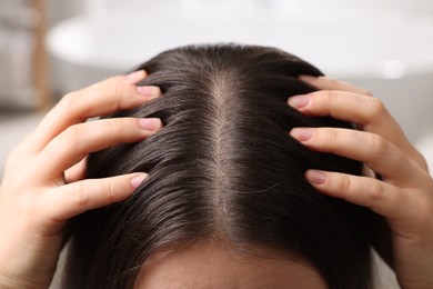 Photo of Woman examining her hair and scalp on blurred background, closeup