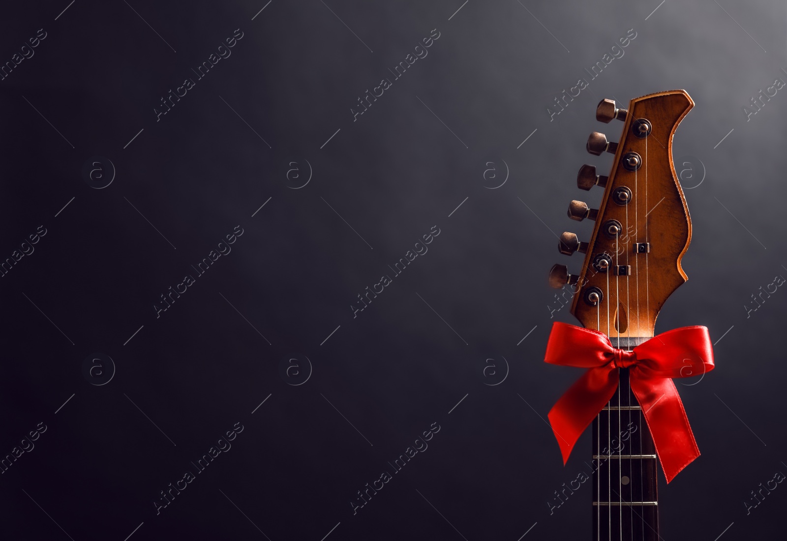 Photo of Guitar with bow on black background. Christmas music concept