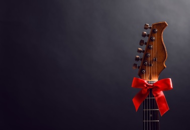 Photo of Guitar with bow on black background. Christmas music concept