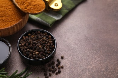 Photo of Aromatic peppercorns and different fresh ingredients for marinade on brown table. Space for text