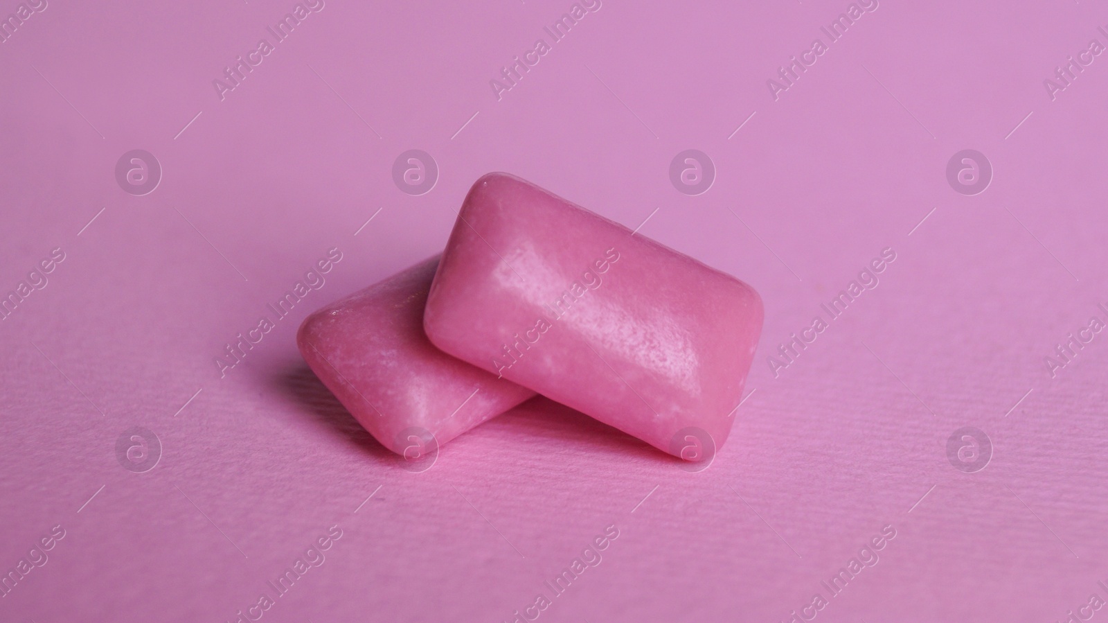 Photo of Tasty sweet chewing gums on pink background, closeup