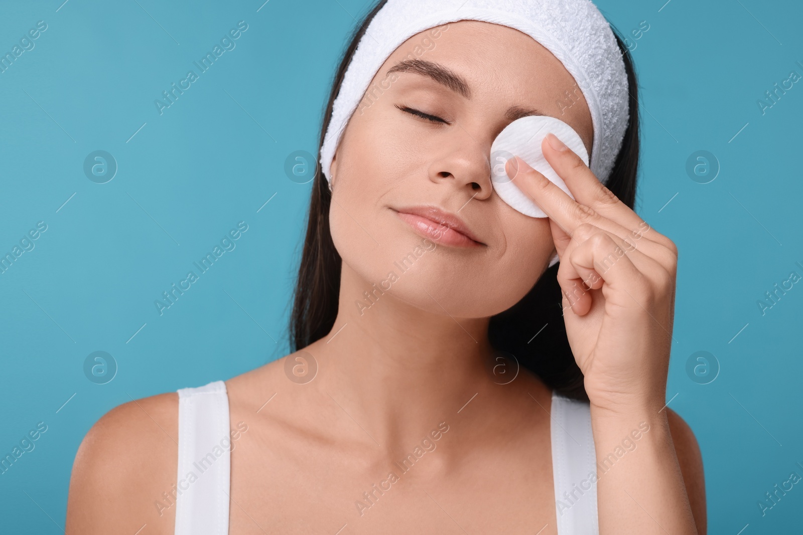 Photo of Young woman with cotton pad on light blue background