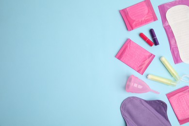 Photo of Tampons and other menstrual hygienic products on light blue background, flat lay. Space for text