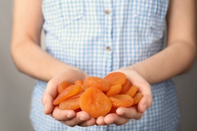 Photo of Woman holding handful of dried apricots, closeup. Healthy fruit