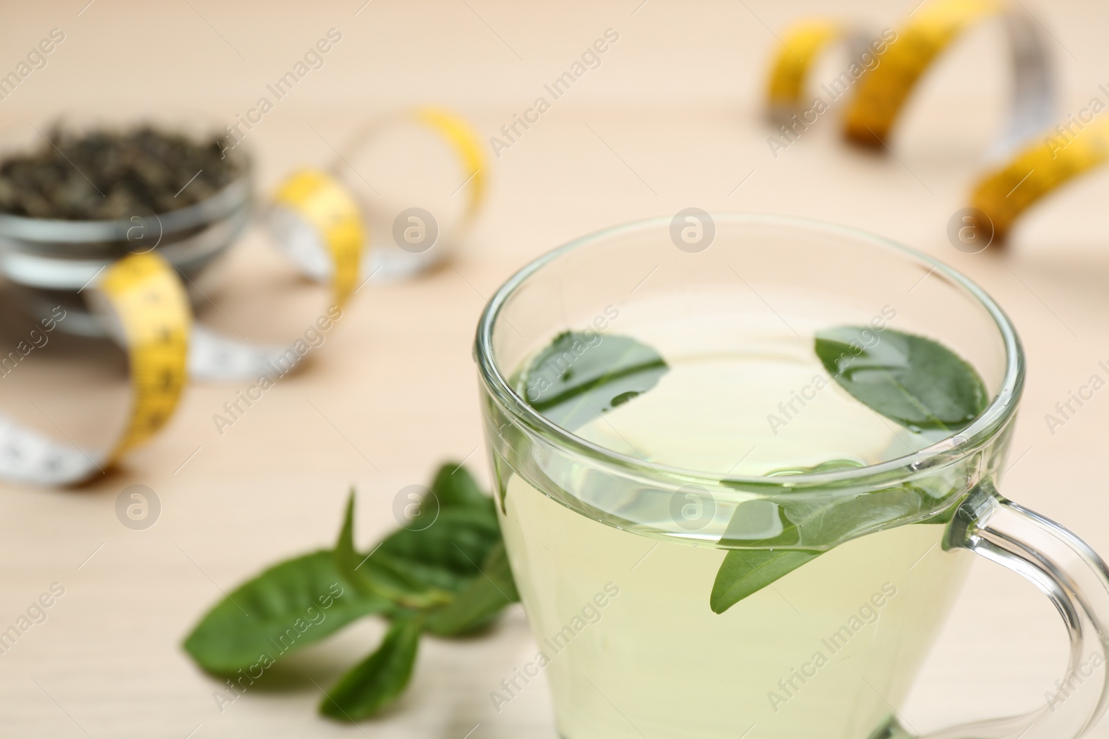 Photo of Diet herbal tea with green leaves on table, closeup. Space for text