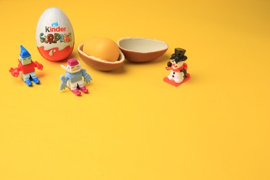 Photo of Sveti Vlas, Bulgaria - June 29, 2023: Kinder Surprise Eggs and toys on orange background, space for text
