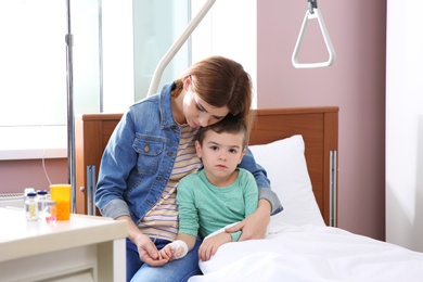 Woman visiting her little child with intravenous drip in hospital