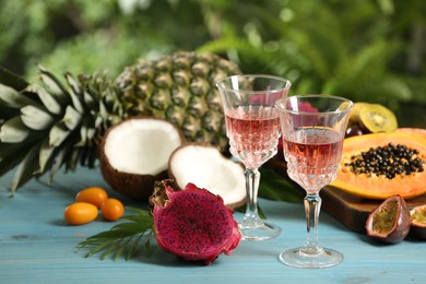 Delicious exotic fruits and wine on light blue wooden table