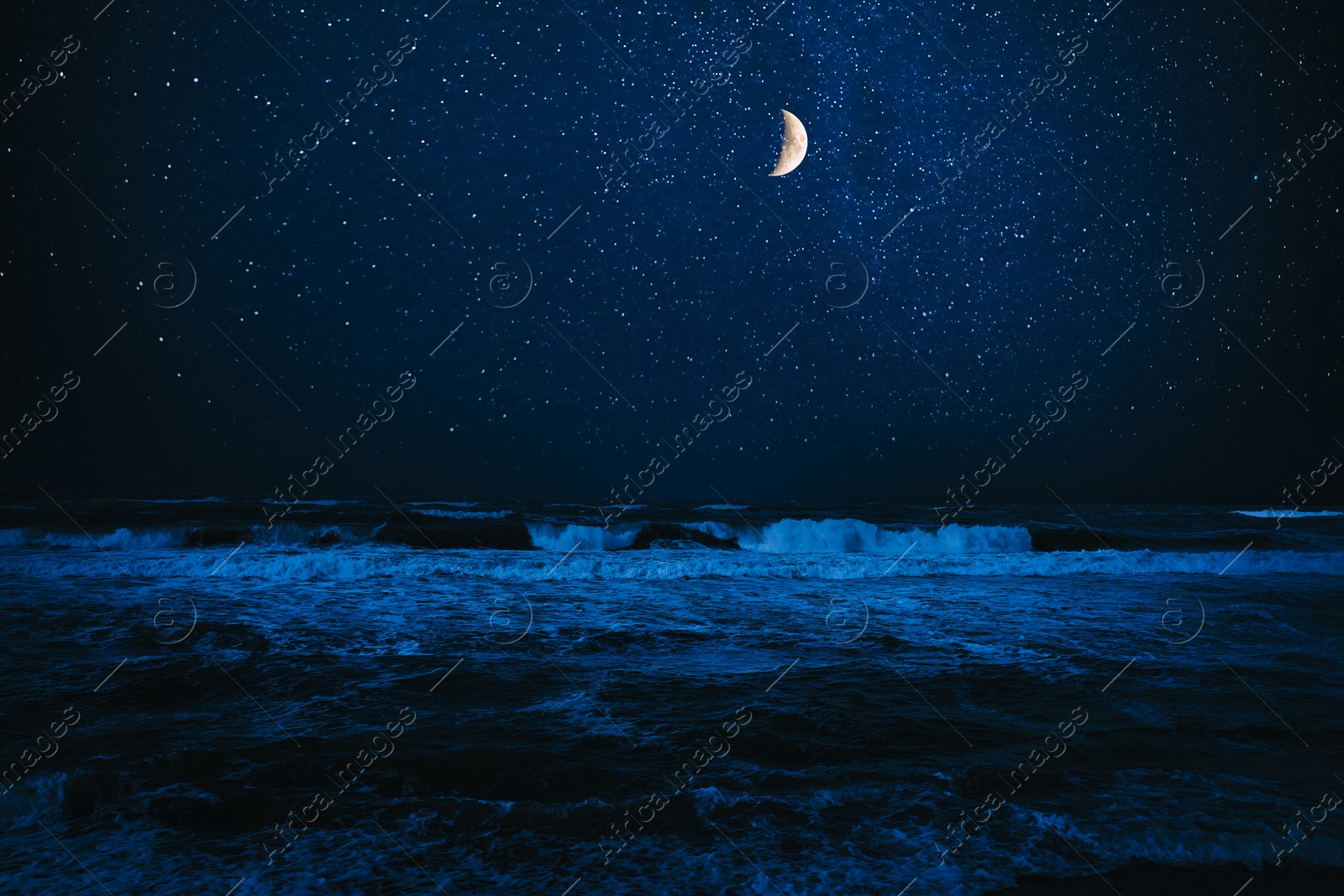 Image of Crescent moon in starry sky over sea at night