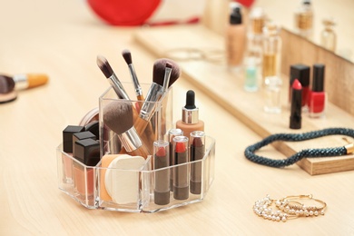 Photo of Organizer with cosmetic products and makeup accessories on dressing table